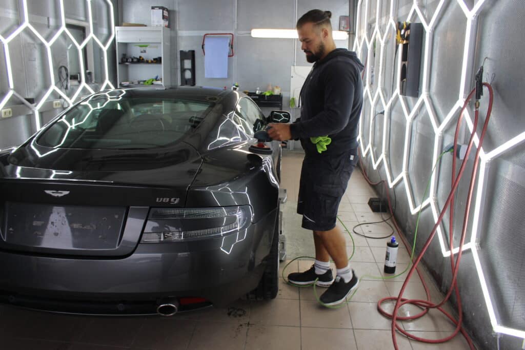 Mann poliert schwarzen Sportwagen in Garage.