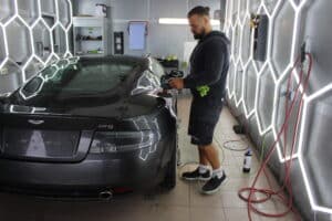 Mann poliert schwarzen Sportwagen in Garage.