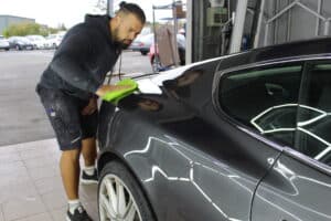Mann poliert schwarzen Autolack mit grünem Tuch.
